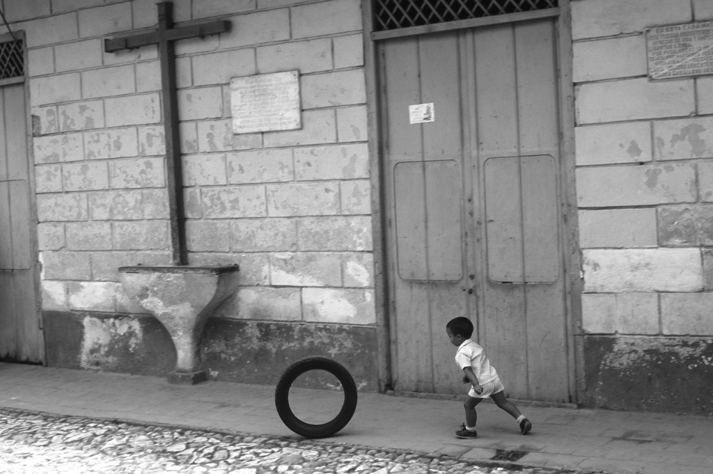 Enfant au cerceau passant près d’un calvaire à Cuba
